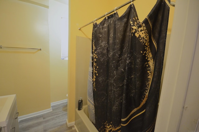 full bathroom featuring vanity, shower / tub combo with curtain, baseboards, and wood finished floors