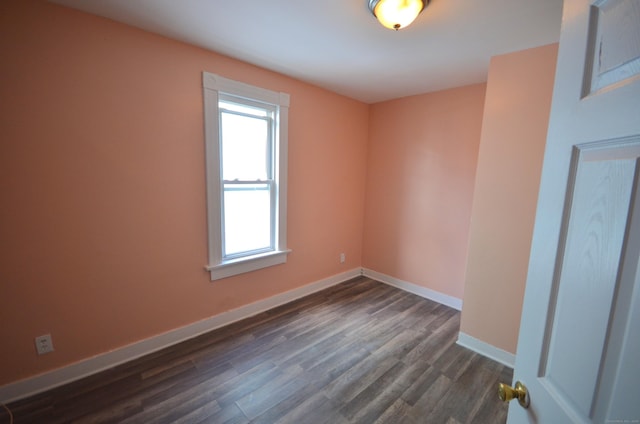 spare room with dark wood-type flooring and baseboards