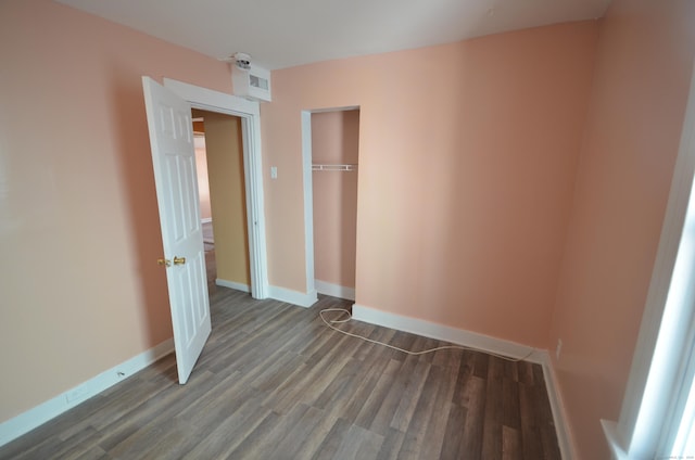 unfurnished bedroom with a closet, baseboards, visible vents, and wood finished floors