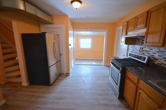 kitchen with tasteful backsplash, under cabinet range hood, brown cabinets, wood finished floors, and stainless steel appliances