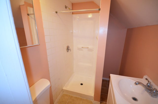 bathroom featuring tile patterned flooring, toilet, vaulted ceiling, a shower, and a sink