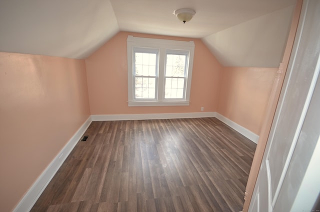 bonus room with visible vents, baseboards, dark wood finished floors, and vaulted ceiling