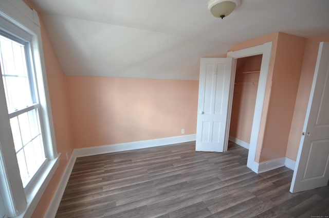 additional living space featuring baseboards, lofted ceiling, and dark wood finished floors