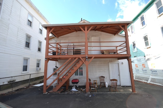 rear view of property with stairs, a deck, and fence