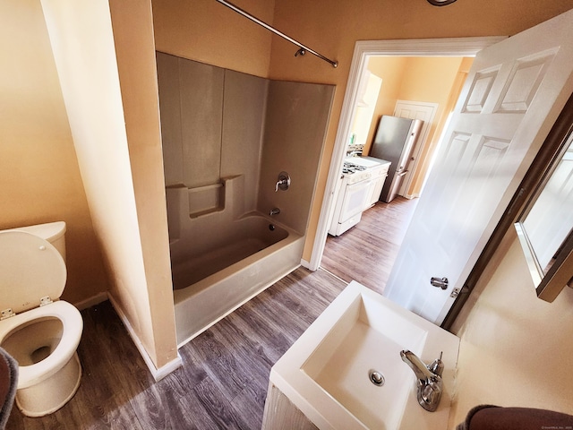 full bath with toilet, wood finished floors, baseboards, and shower / bathtub combination