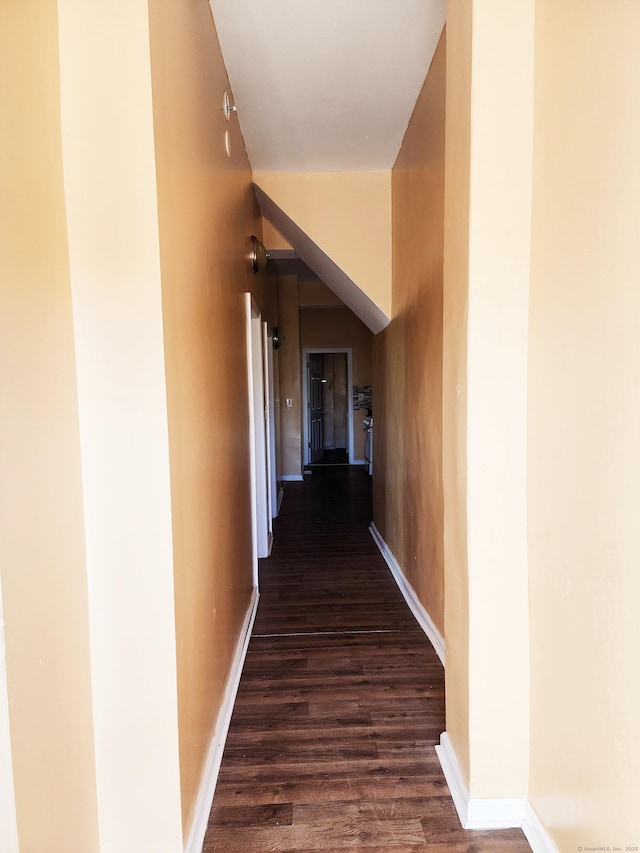 hall featuring dark wood-type flooring and baseboards