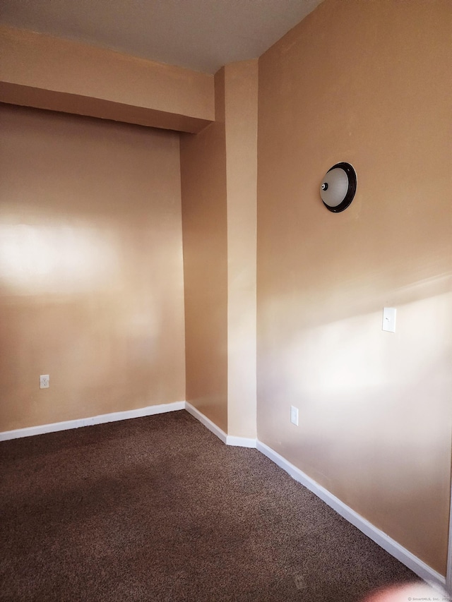 empty room with baseboards and dark carpet