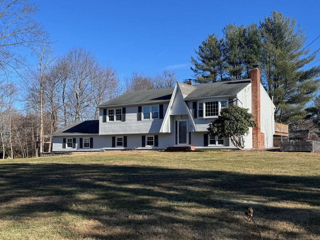 bi-level home featuring a front yard and a chimney