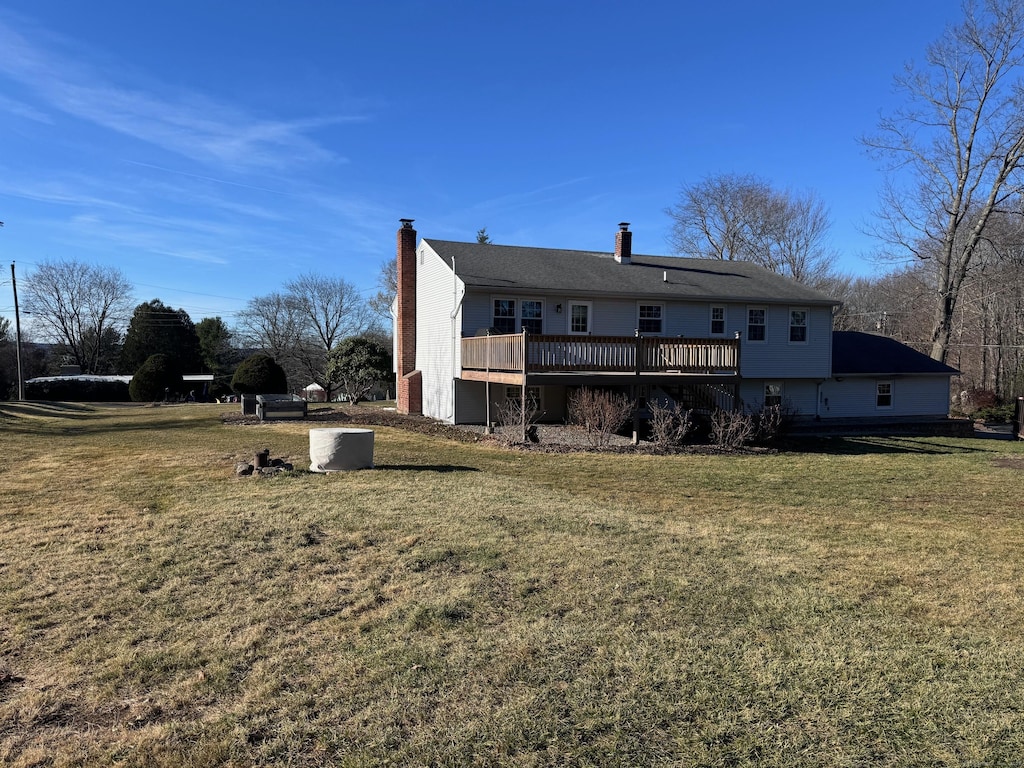 rear view of house with a lawn, a chimney, and a wooden deck