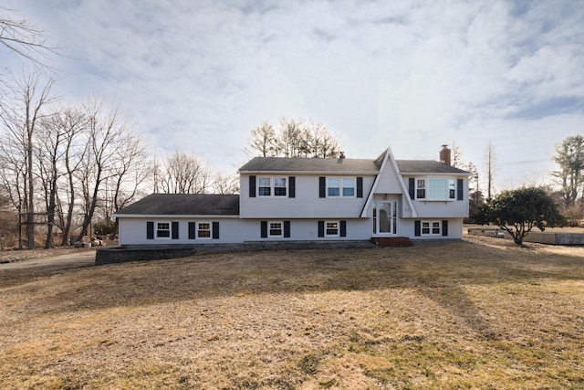 raised ranch with a front lawn and a chimney