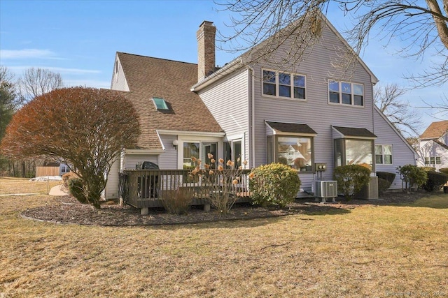 back of house with roof with shingles, a chimney, a lawn, central AC, and a wooden deck