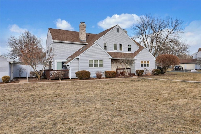 rear view of house featuring a wooden deck, a chimney, and a yard