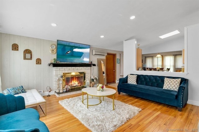 living room featuring lofted ceiling with skylight, a fireplace, wood finished floors, and a wall mounted air conditioner