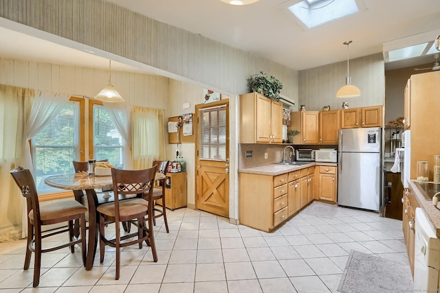 kitchen featuring a skylight, light countertops, decorative light fixtures, and freestanding refrigerator