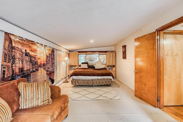 bedroom featuring a baseboard heating unit, lofted ceiling, and wood walls