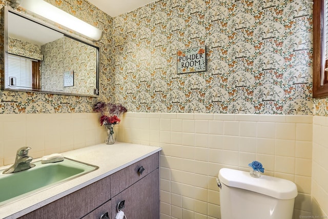 bathroom featuring wainscoting, vanity, toilet, and wallpapered walls