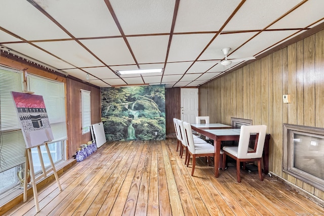 dining space featuring light wood-style floors and wooden walls