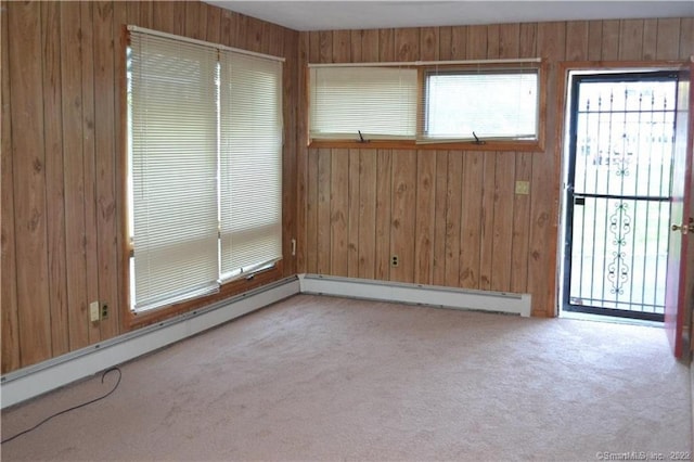 unfurnished room featuring carpet floors, wood walls, a baseboard heating unit, and baseboard heating