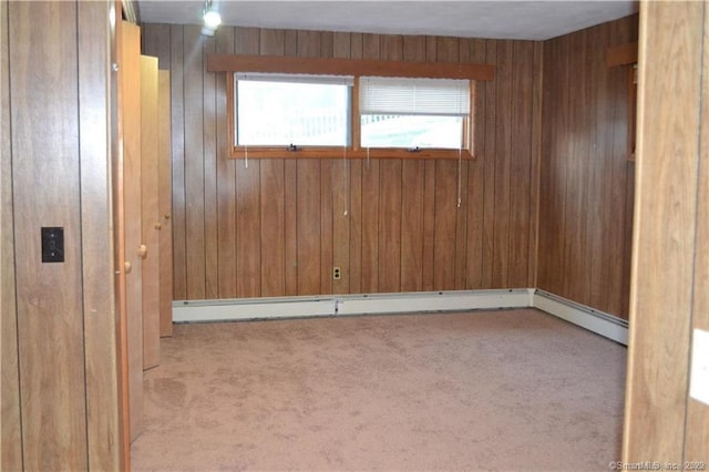 carpeted empty room featuring a baseboard radiator and wooden walls