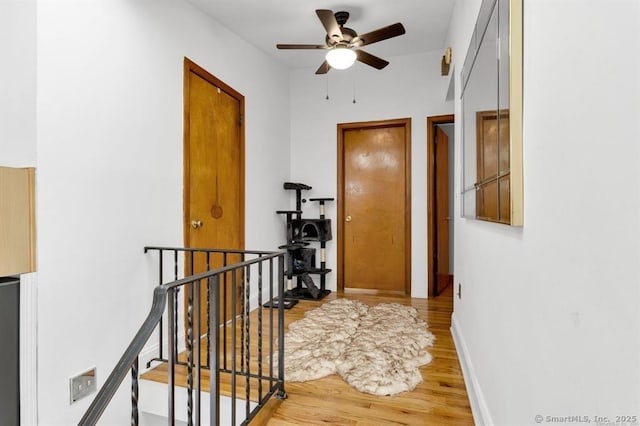 hall with baseboards, light wood-style flooring, and an upstairs landing