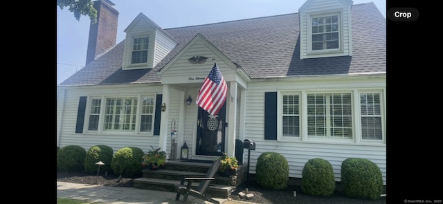 cape cod-style house featuring a chimney and roof with shingles