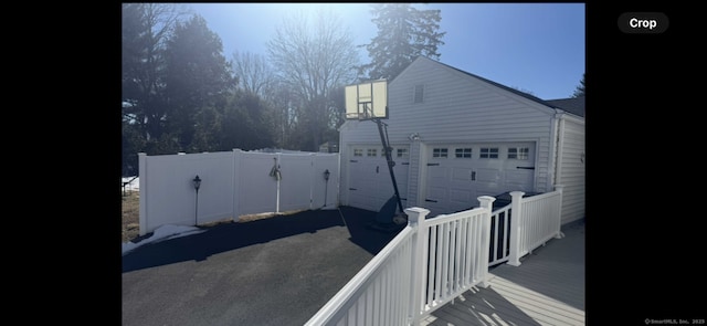 view of home's exterior with an outdoor structure, fence, a garage, and driveway