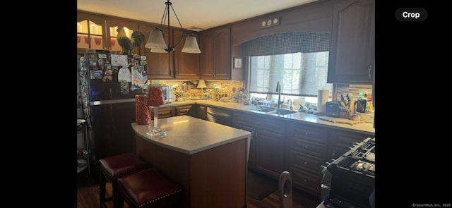 kitchen featuring black appliances, a sink, backsplash, a center island, and light countertops