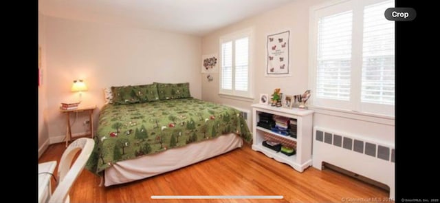 bedroom with radiator and wood finished floors