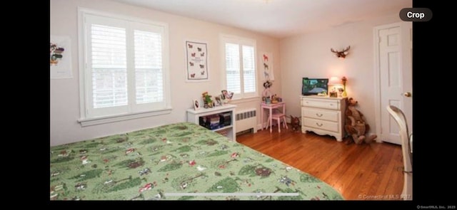 bedroom with radiator and wood finished floors