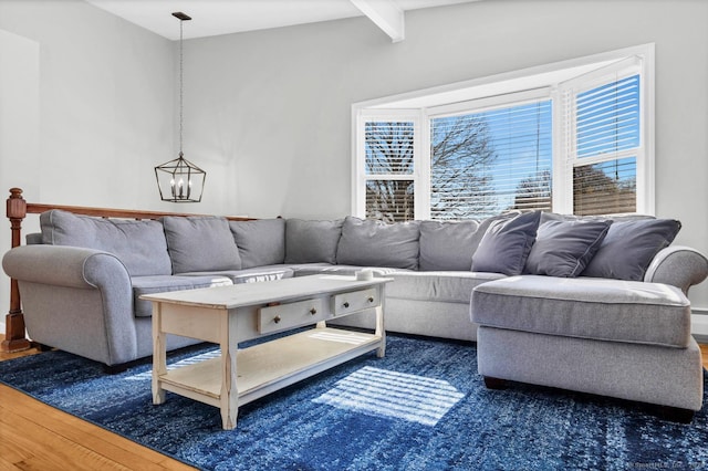 living room with a chandelier, beam ceiling, and wood finished floors