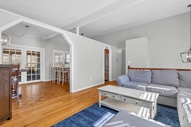 living area featuring baseboards, a chandelier, french doors, arched walkways, and parquet floors