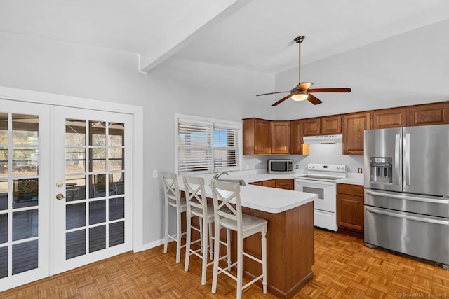 kitchen featuring under cabinet range hood, a sink, appliances with stainless steel finishes, a peninsula, and light countertops