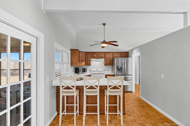 kitchen with a peninsula, light countertops, brown cabinets, and stainless steel appliances