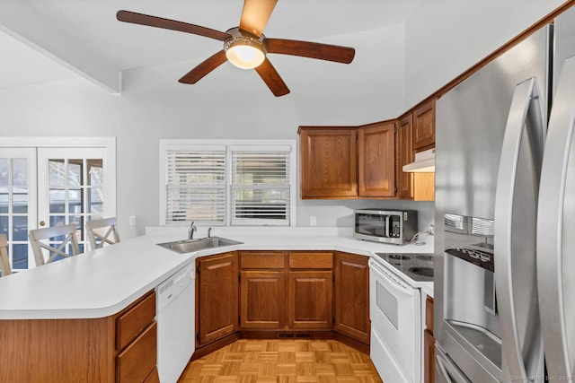 kitchen with brown cabinets, a sink, under cabinet range hood, stainless steel appliances, and light countertops