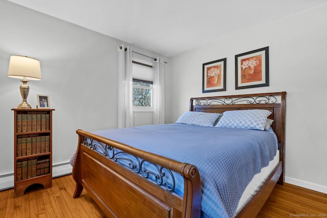 bedroom with baseboard heating, baseboards, and wood finished floors