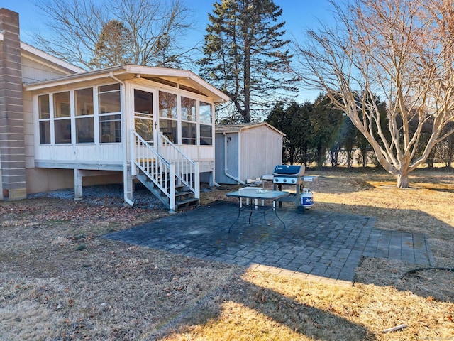 view of yard with a sunroom, an outdoor structure, a shed, and a patio area