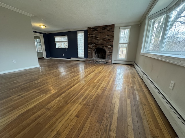 unfurnished living room featuring a brick fireplace, hardwood / wood-style floors, baseboard heating, and crown molding