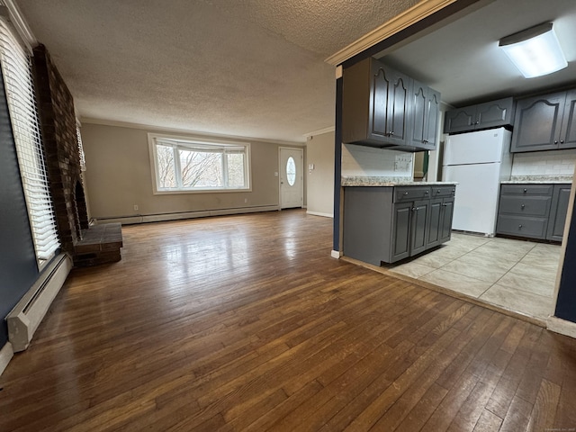 kitchen with open floor plan, light countertops, baseboard heating, and freestanding refrigerator