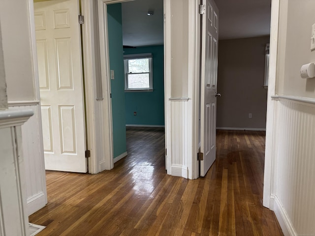 corridor with wood-type flooring and baseboards