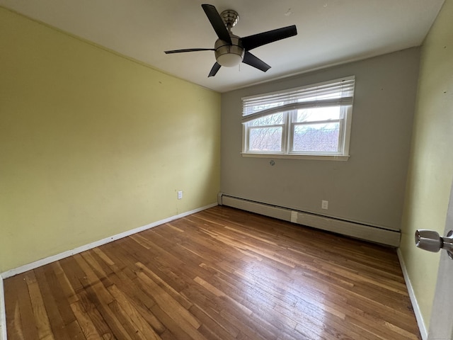 spare room featuring a ceiling fan, wood-type flooring, a baseboard heating unit, and baseboards