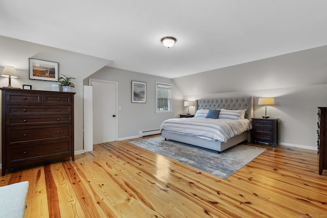 bedroom with lofted ceiling, light wood finished floors, baseboards, and baseboard heating