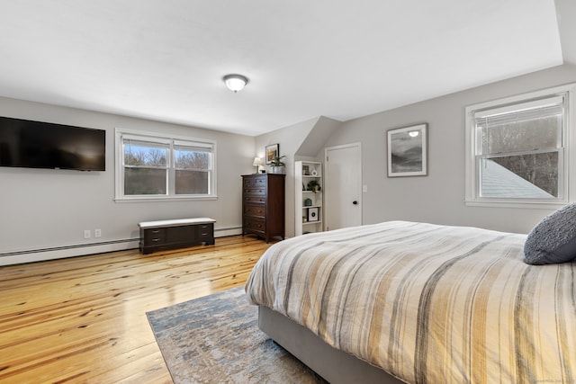 bedroom with wood finished floors and a baseboard radiator