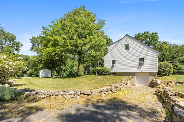 view of side of home with an outbuilding, a lawn, driveway, a shed, and an attached garage