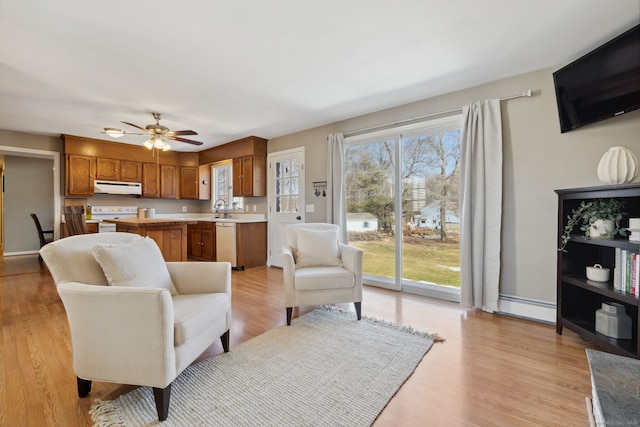 living area with light wood-style flooring, a ceiling fan, and baseboard heating