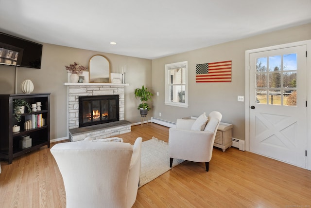 living room with a fireplace, baseboards, light wood-style floors, and a baseboard radiator