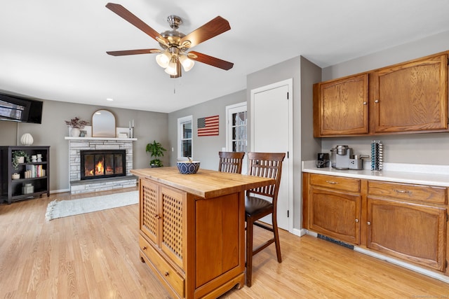 kitchen with wood counters, brown cabinets, light wood-style floors, and a fireplace