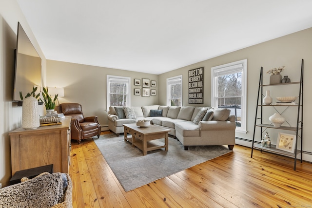 living area with a wealth of natural light, light wood-style flooring, and a baseboard radiator