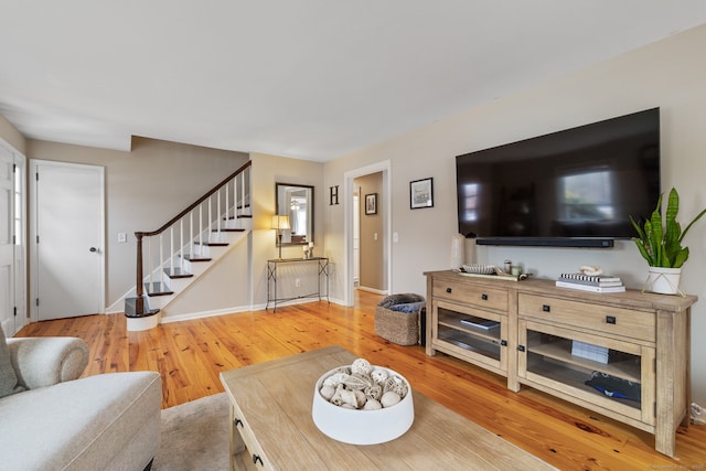 living area with stairway, baseboards, and wood finished floors