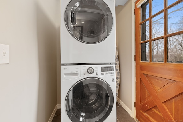 laundry area with laundry area, stacked washing maching and dryer, and baseboards