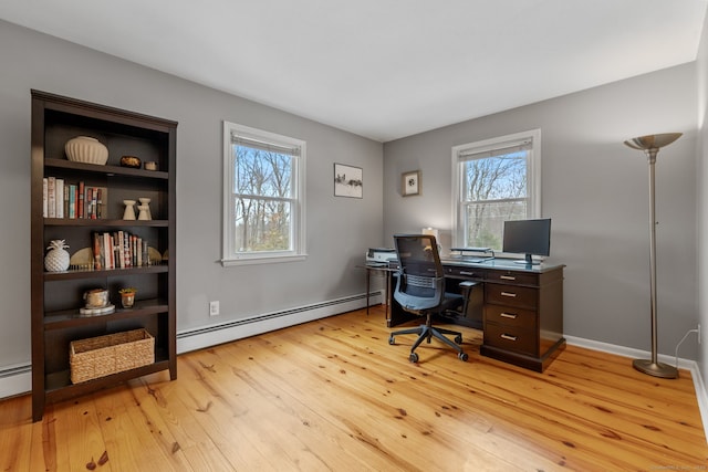 office featuring a baseboard heating unit, baseboards, and light wood finished floors